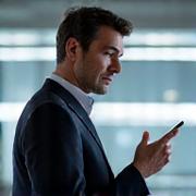 Portrait of an innovative male tech strategist, looking thoughtfully at a sophisticated device